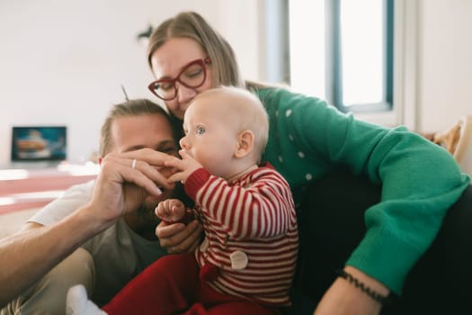 A heartwarming scene of a loving family joyfully interacting with their adorable baby in the comfort of their home