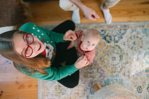 A joyful and heartwarming moment capturing a woman wearing glasses, as she plays with a baby indoors