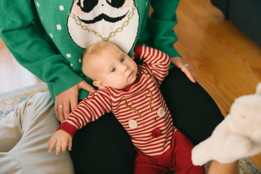 An irresistibly adorable baby dressed in colorful festive attire is joyfully enjoying a playful moment