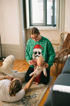A joyful scene of a family bonding in festive attire alongside a cute, playful doll for the holiday season