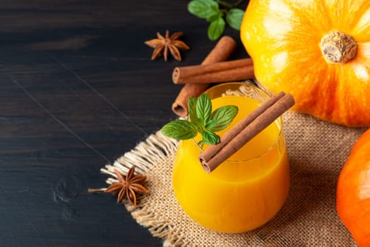 Pumpkin beverage with cinnamon and mint on a rustic table setting.