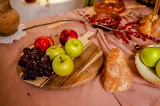 red and green apples, dark blue grapes nearby lie on a wooden board. fruits and bread on a table covered with a dark red pastel tablecloth, beautiful still life