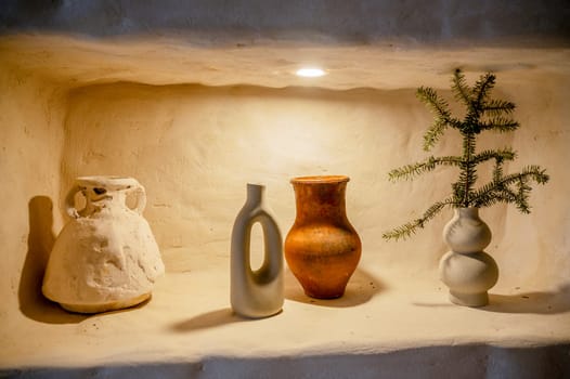 decorative clay products as an element of decor. vases and jugs imitate handwork. are environmentally friendly products made of natural materials. four items on one shelf