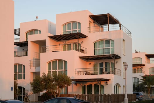 Rows of elegant villas capture the warm hues of sunset, creating a serene coastal atmosphere with a soft breeze.