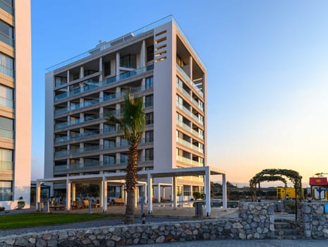 A striking modern structure overlooks the coastline, bathed in warm sunset hues, inviting relaxation and exploration.