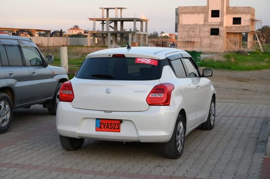 Gaziveren Cyprus -30.01.2025 A modern white car is parked beside a developing construction site during the warm hues of sunset.