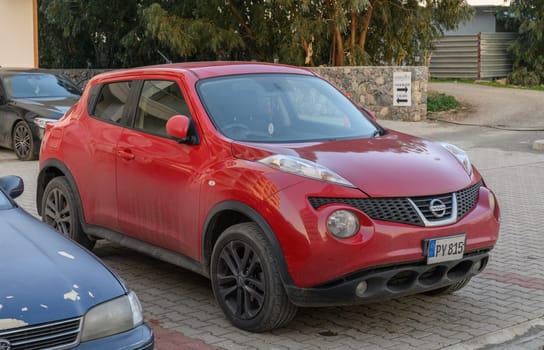 Gaziveren Cyprus -30.01.2025 A vibrant red compact vehicle stands out among parked cars in a serene urban environment on a sunny day.
