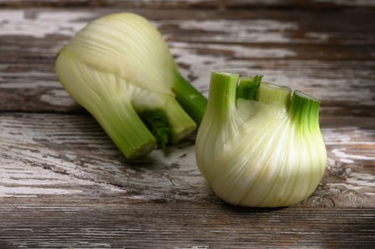 Organic fennel bulb sits beautifully on a weathered wood table, highlighting its unique shape and fresh hue.