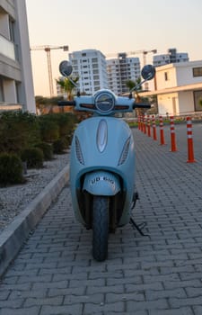 Gaziveren Cyprus -30.01.2025 A sleek, pastel-colored electric scooter stands proudly on a contemporary brick pathway at sunset.