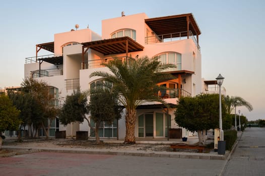Modern architecture stands amidst palm trees at dusk in a serene coastal setting.