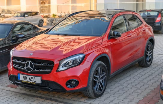 Gaziveren Cyprus -30.01.2025 A stunning red luxury SUV rests in a contemporary parking lot as the sun casts warm afternoon shadows.