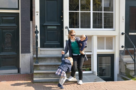 Mother and small left the house for a walk or to kindergarten or school in Amsterdam.