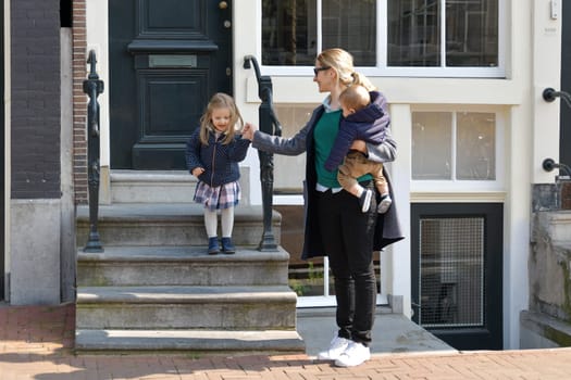 Mother and small left the house for a walk or to kindergarten or school in Amsterdam.