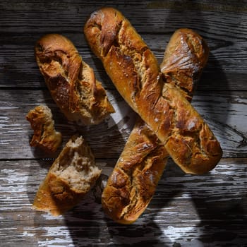 Crusty bread loaves sit atop an aged wooden surface, bathed in soft light, inviting a moment of delicious indulgence.