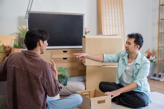Two men sitting on the floor, discussing and unpacking boxes in their new living room, capturing the joy and excitement of moving together as they create a cozy space.