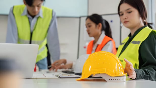 Professional construction team discussing project plans while showcasing yellow safety helmets in a contemporary workspace.