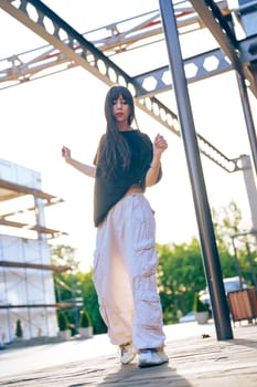 In a vibrant outdoor setting, a young woman dances with elegance as the sun sets, surrounded by striking modern architecture and lush greenery, creating an inspiring atmosphere.