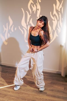 A dancer showcases her skills in a chic room, wearing casual attire. The warm light creates intriguing flame-like shadows, enhancing the artistic atmosphere as she moves gracefully.