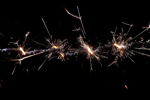 Glowing sparklers against dark background with vibrant sparks.