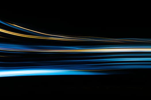 Abstract light trails in motion on a black background.