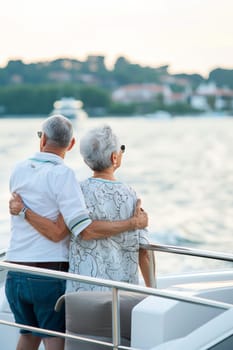 Elderly caucasian couple embracing on a boat at sunset.