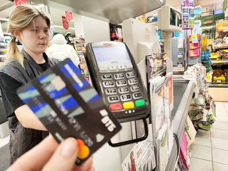 Kirov, Russia - November 21, 2024: Customer completes a payment using a bank card at a busy grocery store checkout during the afternoon hours.