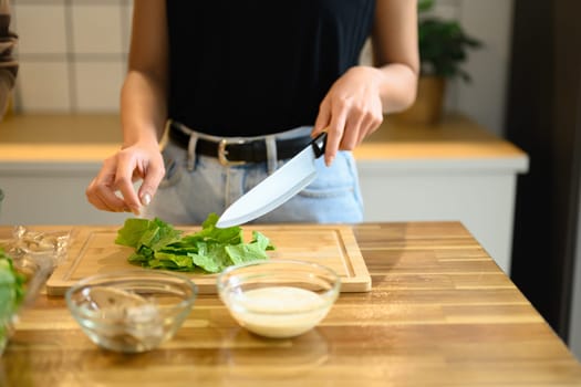 Young woman preparing healthy vegetable salad in minimal kitchen.