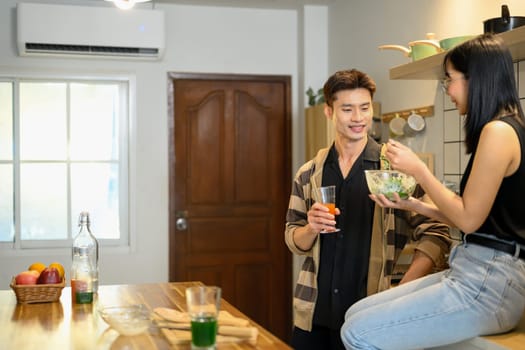 Romantic couple eating a fresh salad together in the kitchen.