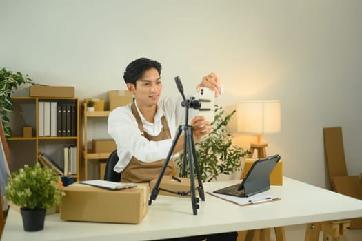 Young small business owner adjusting smartphone for live streaming product.