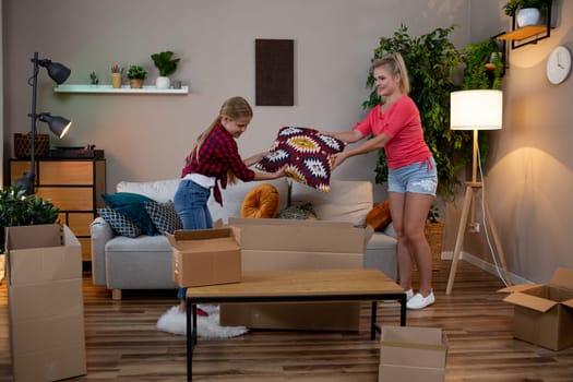 Two close friends happily unpack boxes and arrange home items while transforming their cozy living room space