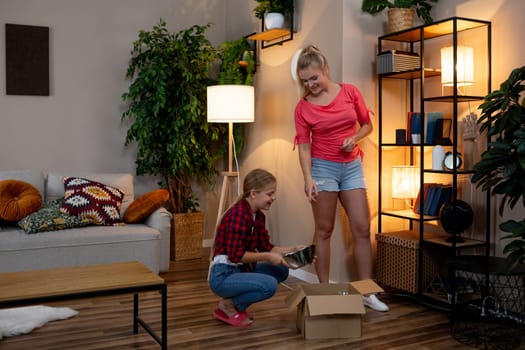 Two women are joyfully unboxing various home decor items in a beautifully stylish interior setting filled with charm