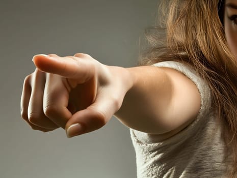A close-up shot of a woman’s hand pointing directly at the viewer. The gesture conveys accusation, command, or emphasis. Dramatic lighting enhances the intensity of the image.