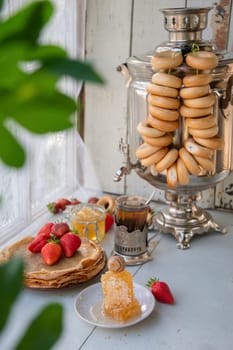 Still life in the Russian tradition for Maslenitsa, pancakes with honey and strawberries, tea from a samovar with bagels, Slavic holiday, High quality photo