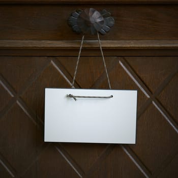 blank white sign with space for text hangs on an entrance door