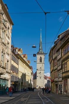 Erfurt, Germany – September 29, 2024: Shopping street with historic buildings and the All Saints' Church, Allerheiligenkirche in the old town of Erfurt in Germany