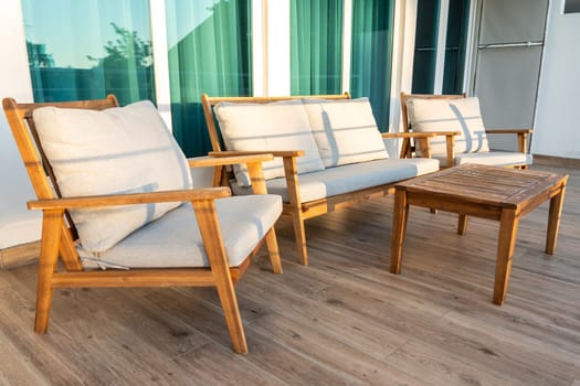 Outdoor seating area with wooden chairs, soft cushions, and matching coffee table on a wooden deck