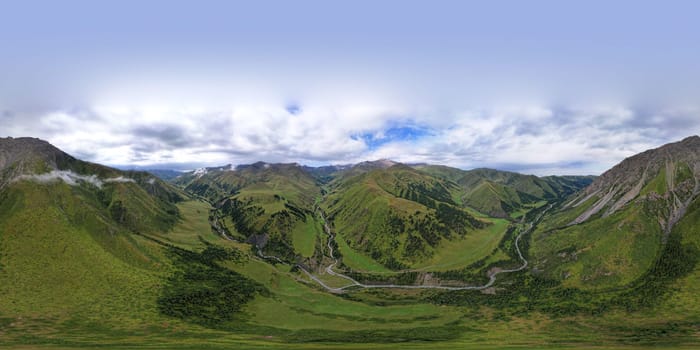360 panorama of a mountainous area from a height. Drone view of green meadows and hills, with coniferous trees in places. A river runs through the forest. White clouds and blue sky. Beautiful gorge.