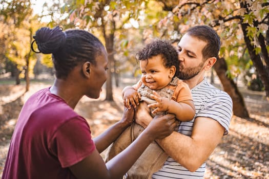 Boy in the arms of his parents in the park.