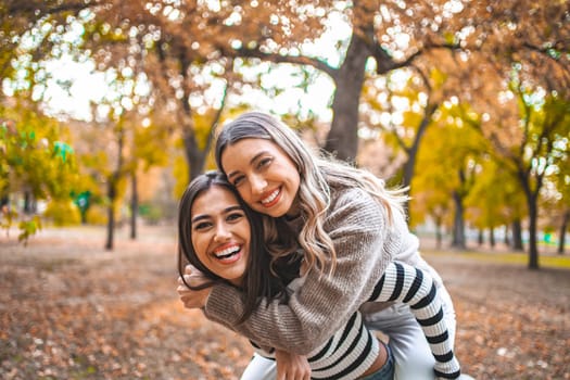 Two women are standing side by side, looking towards the camera. They appear to be chatting or conversing casually while standing in a relaxed posture.