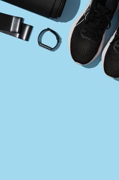 Fitness background with mat, fitness rubber band, strap, sneakers on blue background. Sports items, healthy lifestyle concept. Place for your text