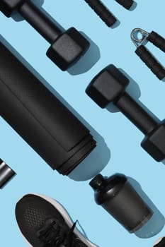 Black workout equipment for training at home on light blue background. Fitness, sport items, healthy lifestyle concept.