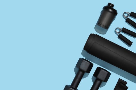 Black workout equipment for training at home on blue background. Fitness, sport items, healthy lifestyle concept. Copyspace