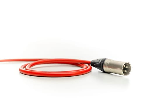 Red audio cable with xlr connector lying on a white background