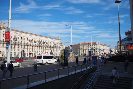 Minsk, Belarus, April 10, 2024: Station Square in front of the railway station. Cars, trucks and buses pass by. People are walking. Sunny spring day. Majestic tower buildings and Kirov Avenue.