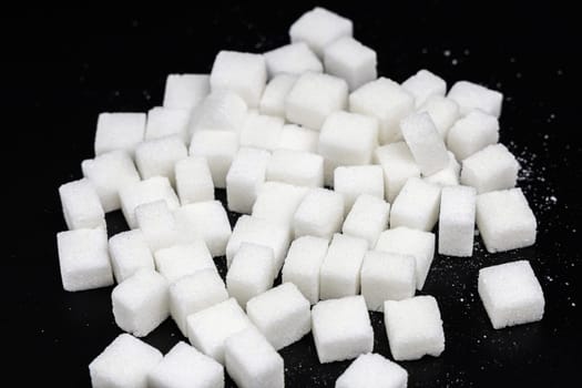 Cubes of white refined sugar on a black background. High quality photo