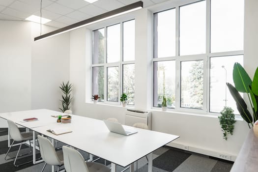 A white table and chairs are neatly arranged in a room, creating a simple and clean aesthetic. The chairs are positioned around the table, ready for use. The room appears spacious, with natural light accentuating the white furniture.