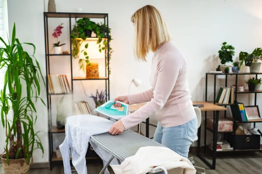 A woman skillfully irons garments in a bright and inviting room.