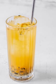 Passion Fruit Caipirinha cocktail in highball glass with straw on white wooden