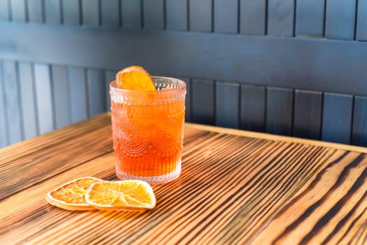 Alcohol cocktail Aperol Spritz with slise of orange on wooden table against dark wall with copy space