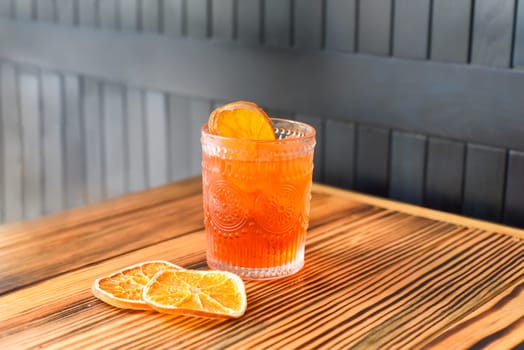 Alcohol cocktail Aperol Spritz with slise of orange on wooden table against dark wall with copy space
